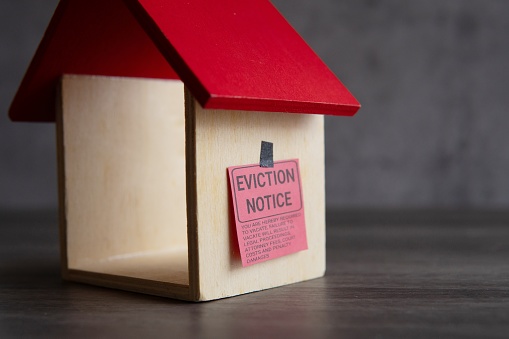 Closeup image of toy house and eviction notice.