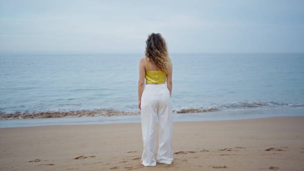 istock Unrecognizable woman standing beach looking picturesque ocean waves alone. 2080827467