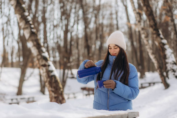 istock Happy young woman drinks hot tea from thermos cup during walk in winter forest 2080863570