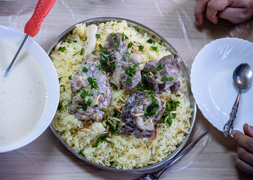 Jordanian mansaf on family table for dinner ready to be eaten looks hot and fresh with meat and almonds topping