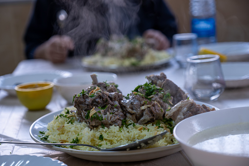 hot fresh mansaf steam with hands around it ready to be eaten on family table for iftar