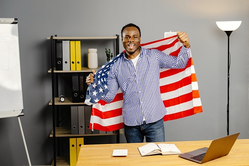 Man holding american flag in front of laptop.