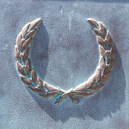 Bronze coat of arms, detail of the monument, close-up. Background is a bronze plate covered with oxide green patina, the surface is rough with scratches and gouges. Rough Bronze Texture with Patina.