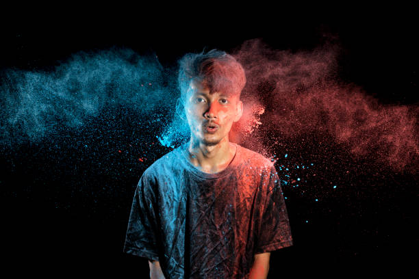 istock Asian man splashed with colorful holi powder and having fun isolated on black background. 2080884183