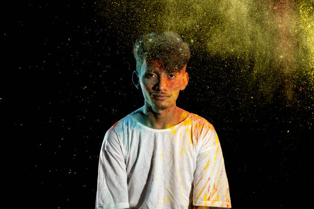 istock Asian man splashed with colorful holi powder and having fun isolated on black background. 2080884731