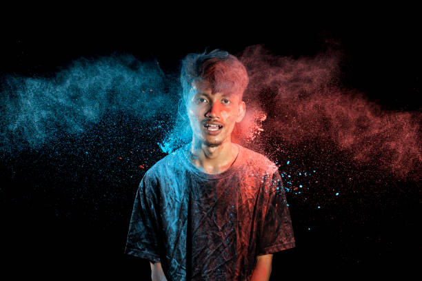 istock Asian man splashed with colorful holi powder and having fun isolated on black background. 2080886825