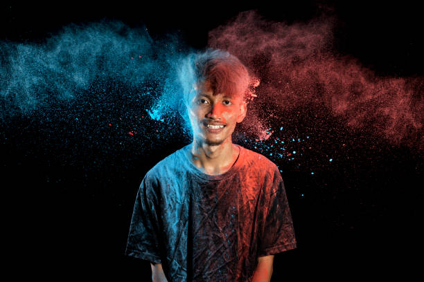 istock Asian man splashed with colorful holi powder and having fun isolated on black background. 2080887865