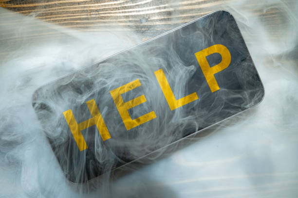 Close up smartphone with smokes and words Help on a wooden desk. Damage equipment.