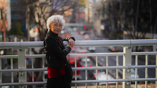 A portrait of a beautiful and confident Asian senior woman with short white hair in the city.