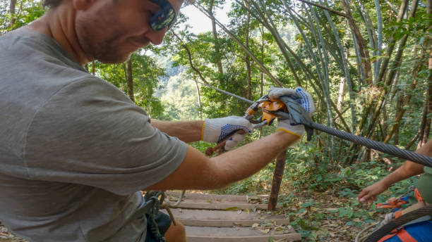 junger mann bereitet sich darauf vor, mit der seilrutsche über den dschungel in laos zu fahren - zip lining stock-fotos und bilder