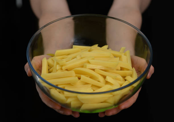 papas amarillas cortadas en palitos para papas fritas en un bol de vidrio - french fries fast food french fries raw raw potato fotografías e imágenes de stock
