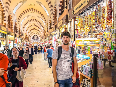 Istanbul, Turkey - October 28, 2019: Young male tourist and many other people in the archway of the Grand Bazaar in Istanbul. People walk through the pavilions of the famous Turkish tourist market