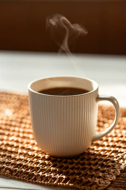 istock A steaming cup with a hot drink in the sunlight on the table. 2080936064
