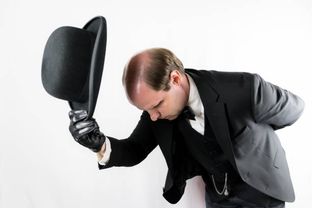 Butler or Hotel Doorman in Suit and Leather Gloves Doffing Bowler Hat and Bowing Courteously