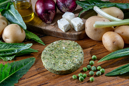 Fresh prepared herb butter on a wooden cutting board with ingredients. Delicious spread food background.