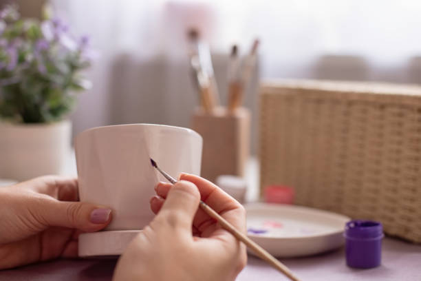 istock Female paints with a brush, on a white ceramic pot 2080959440