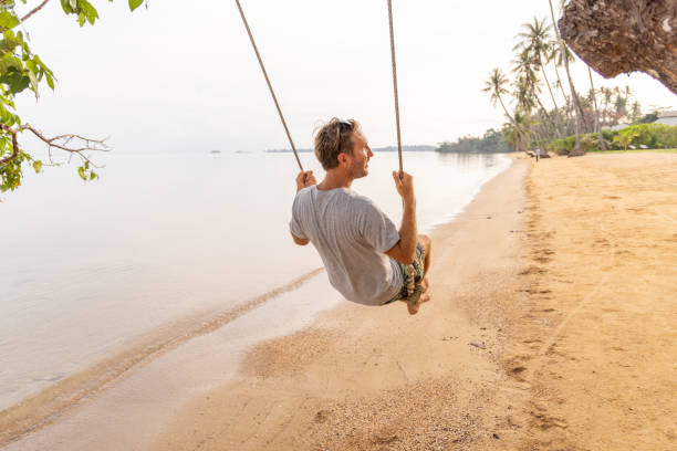 istock Young man plays swing on a wild beach 2080973013