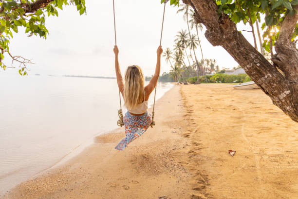 istock Young woman plays swing on a wild beach 2080975132