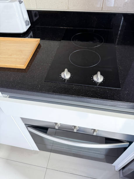 istock Image of modern kitchen units with halogen hob, compact cooker, white gloss breadboard, and sleek black granite worktop and countertop 2080975667
