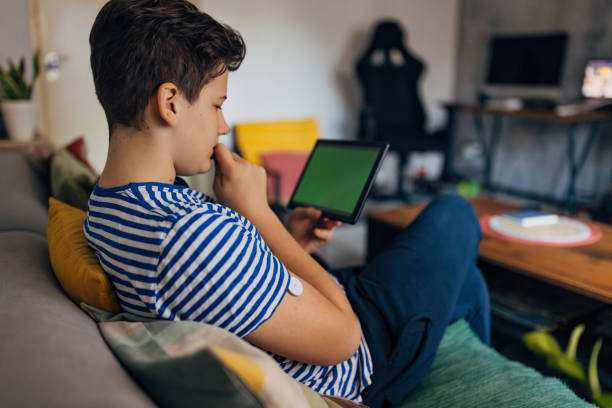 istock Teenage boy with diabetes wearing a small glucose sensor and using a digital tablet with green screen 2080978959