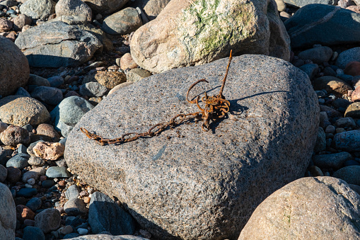 An old rusted chain lies on a large rock surrounded by diverse smaller stones.