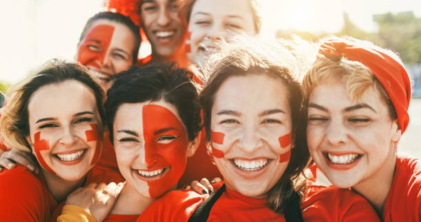 istock Crazy sport fans smiling on camera  while supporting their team - Football supporters having fun outside of stadium wearing red t-shirts - Event and betting concept - Focus on girl with short hair 2080983669