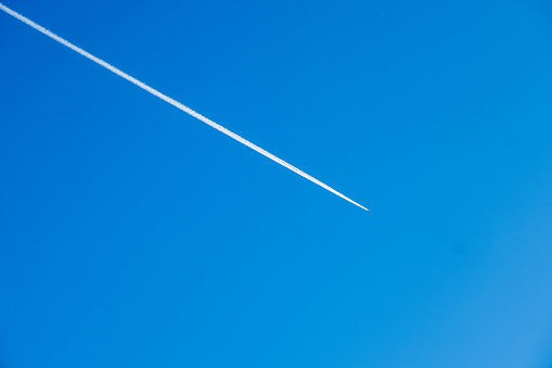 A distinct white airplane contrail against a vivid blue sky.