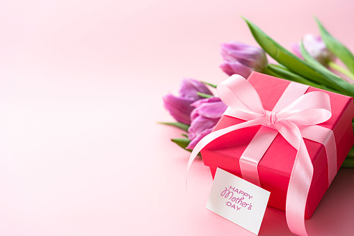 Mother's Day design concept background with tulips and gift on pink background. Copy space. High resolution 42Mp studio digital capture taken with Sony A7rII and Sony FE 90mm f2.8 macro G OSS lens