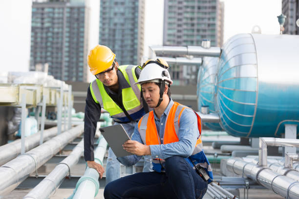 istock Group of Asian male engineer working at construction site area. Male engineer worker standing near sewer pipes or water tank area. Team of male plumber worker maintenance sewer pipes network system 2080994726