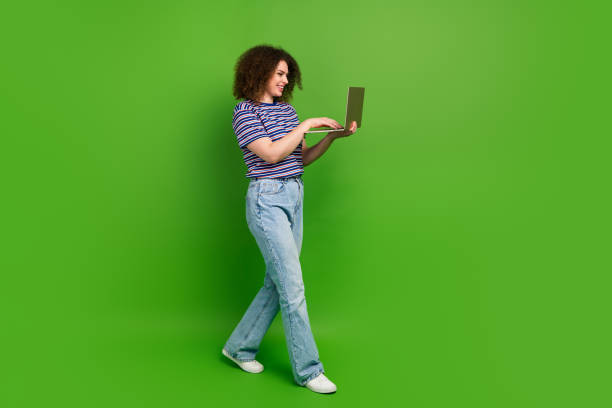 istock Full size profile portrait of cheerful girl use netbook texting walk empty space ad isolated on green color background 2080998436