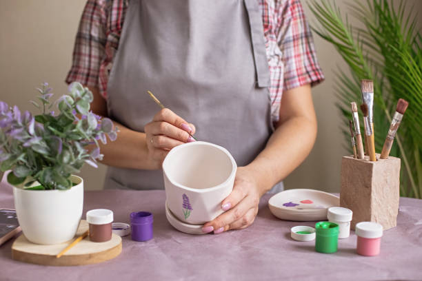 istock Women in gray apron paint a white flower ceramic pot 2081032941