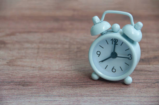 White alarm clock pointing at 8am on wooden table. Copy space and time concept.