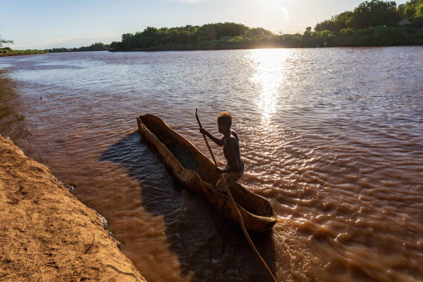 passeur sur un bateau grossier en bois sur la mystique rivière omo, éthiopie - asian tribal culture photos photos et images de collection