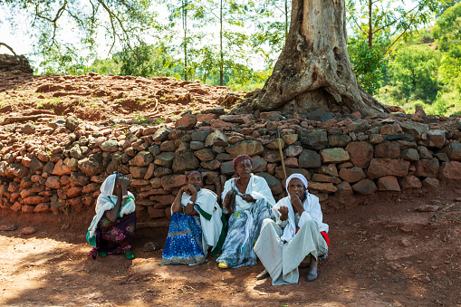 Lalibela, Ethiopia - May 1, 2019: Orthodox Ethiopians unwind at St. George Church after Mass. A serene moment capturing faith and cultural richness.