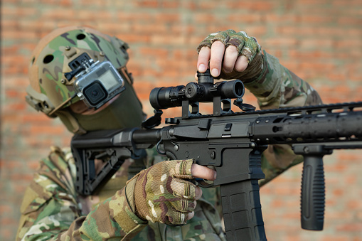Military with a close-up optical sight, adjusting the sight when shooting