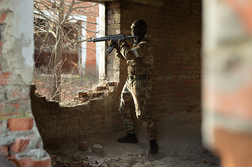 A terrorist during the fighting in an urban area. A ruined brick building