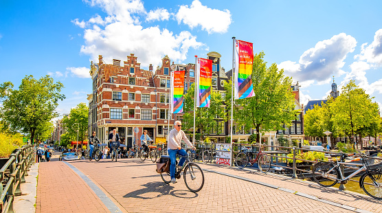 Amsterdam, Netherlands - 26 July, 2023: Scenic view of Amsterdam city centre. People riding a bicycles.