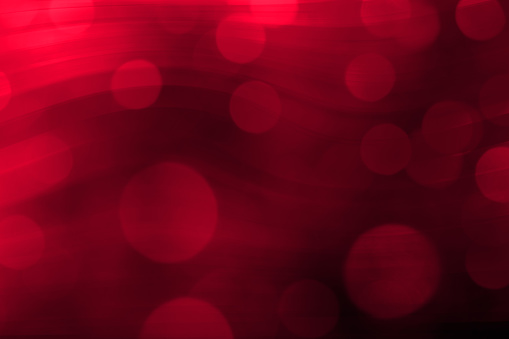 Abstract wavy background in red tones with defocused bokeh light. Space for copy.