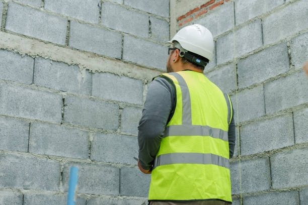 istock Asian construction manager with tablet, white helmet, speaking on walkie-talkie, supervising site. Worker in safety vest, holding tablet and radio, attentive, managing construction project outdoors 2081165406