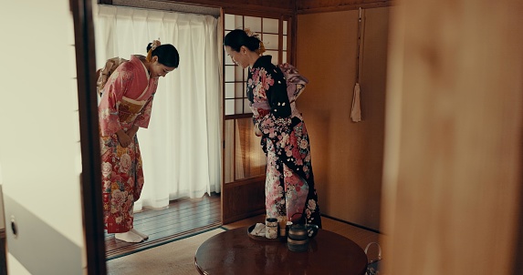 Traditional, bow and Japanese women with tea for culture with leaves and herbs in tearoom. Friends, ceremony and people with herbal beverage for wellness, mindfulness and detox for drinking ritual