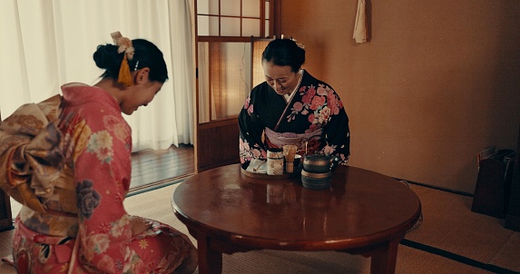 Culture, home and Japanese women with tea, leaves and herbs in traditional tearoom. Friends, ceremony and people bow with herbal beverage for wellness, mindfulness and detox for drinking ritual