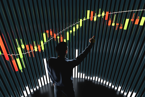 Price chart with volumes. The trader analyzes the price movement on a huge trading chart. A businessman-investor watches the movement of the price of an asset.