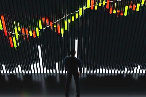 Price chart with volumes. The trader analyzes the price movement on a huge trading chart. A businessman-investor watches the movement of the price of an asset.