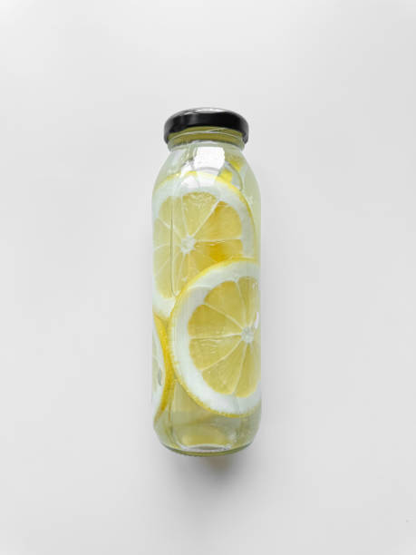 Detox drink with sliced limon in inside glass bottle, isolated on white background. High angle view with copy space. Freshness and hydration concept for health and wellness design. High quality photo