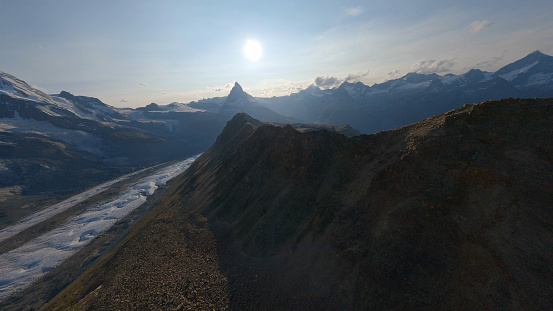 Aerial view of crevasse field on glacier leading to mountains at sunrise, Swiss Alps