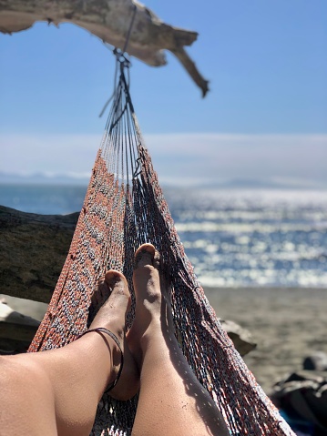 Personal perspective from woman lying in hammock on beach and ocean distant