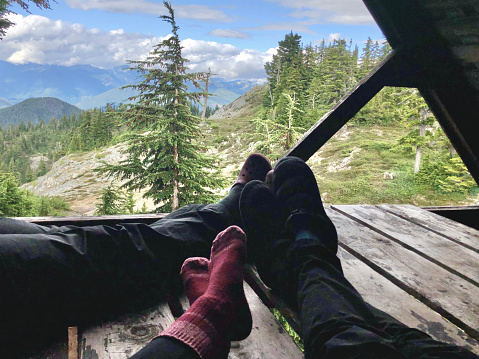 Personal perspective of a group of feet resting on a camp vehicle above a forest and mountains, Mount Steele, Sunshine Coast