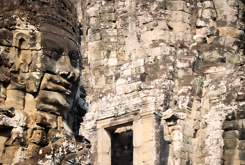 One of the stone faces of Bayon Temple in  Angkor Thom. Bayon's most distinctive feature is the multitude of smiling stone faces (probably modeled on the face of King Jayavarman VII) on every side of the upper terace towers, Siem Reap, Cambodia