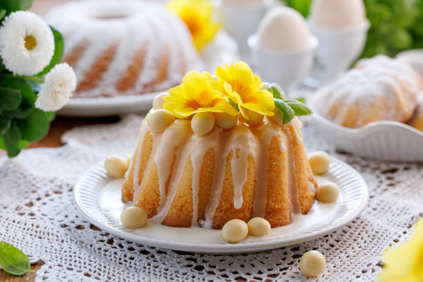 Traditional Easter cake, Babka covered with icing decorated with chocolate eggs and primrose flowers on a festive table