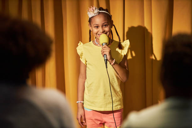 istock Smiling Girl Speaking To Microphone Performing for Parents 2081375907